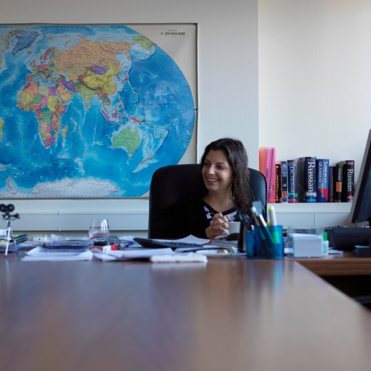 Margarita Simonyan, editor-in-chief of Russia Today, sits at her desk with a world map behind her.