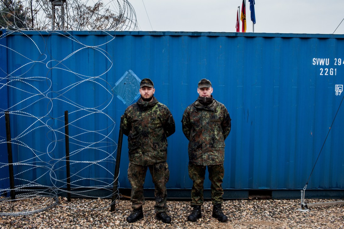 Two German soldiers in camouflage uniforms stand in front of a blue military container at Gazi base in Turkey.