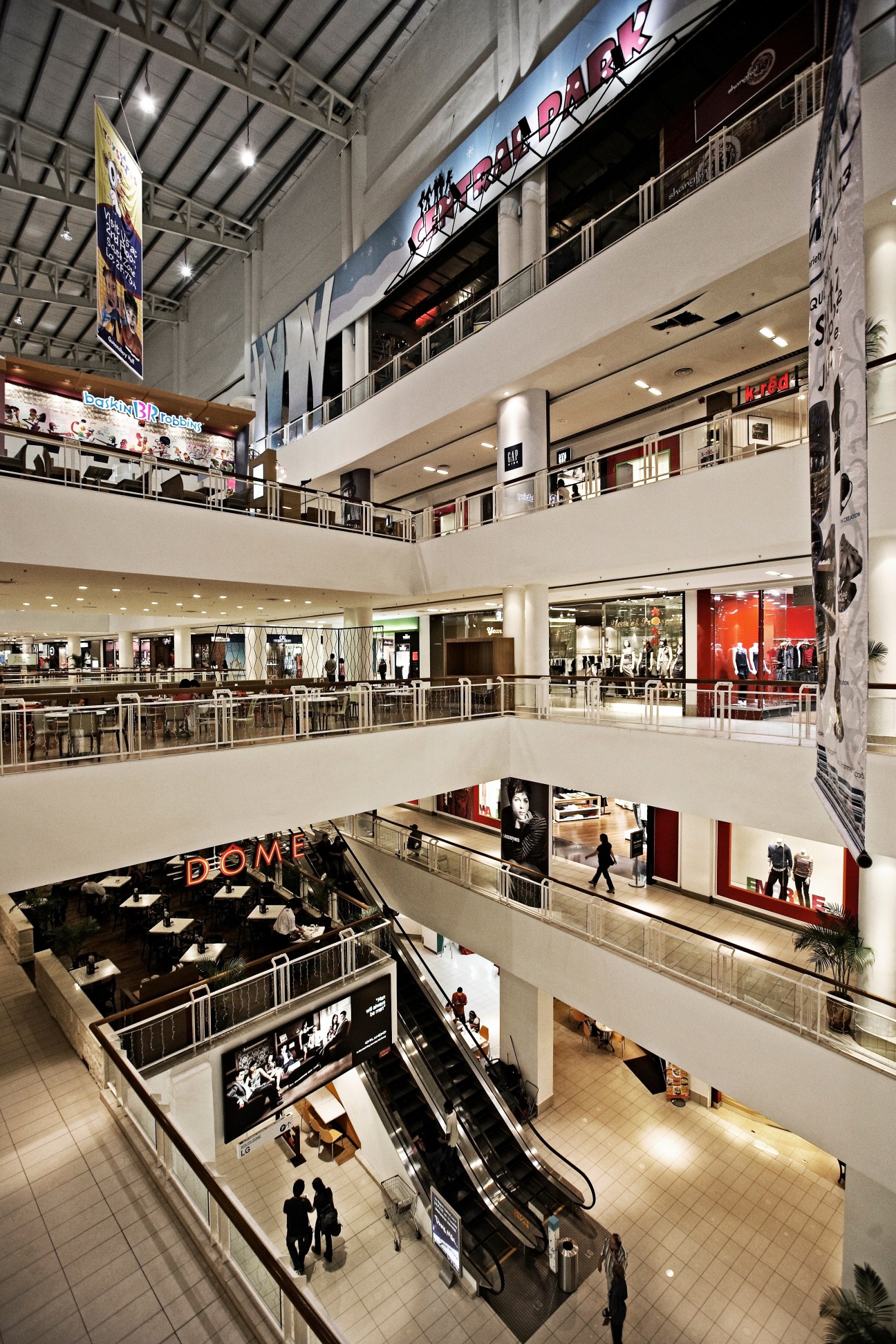 Interior of Queensbay shopping mall with multiple levels, escalators, and retail storefronts.