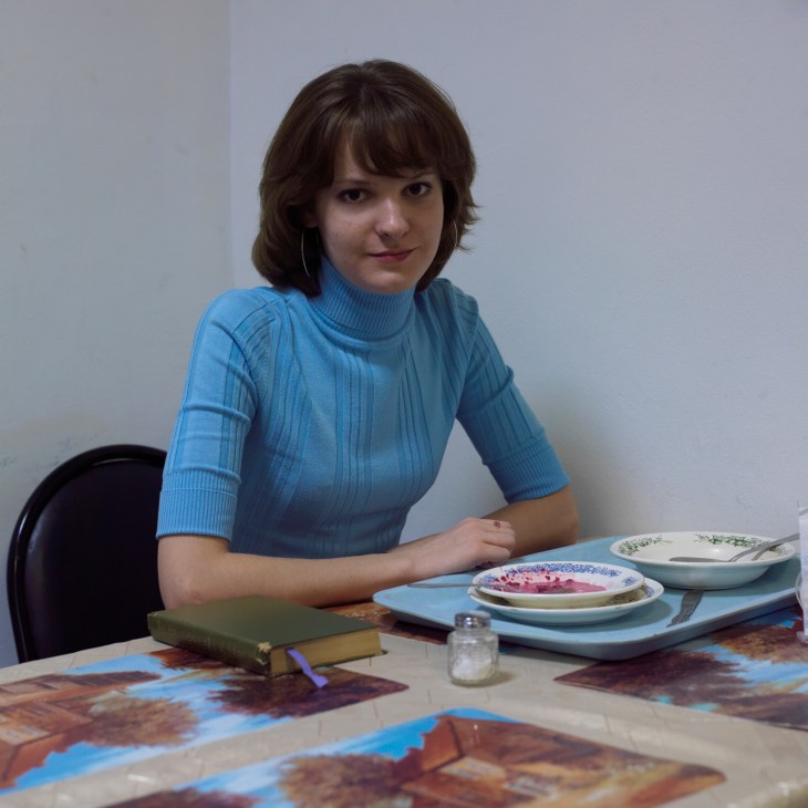 Dasha Zhdanova, a Russia Today producer, sits at a table with decorative plates during lunch.