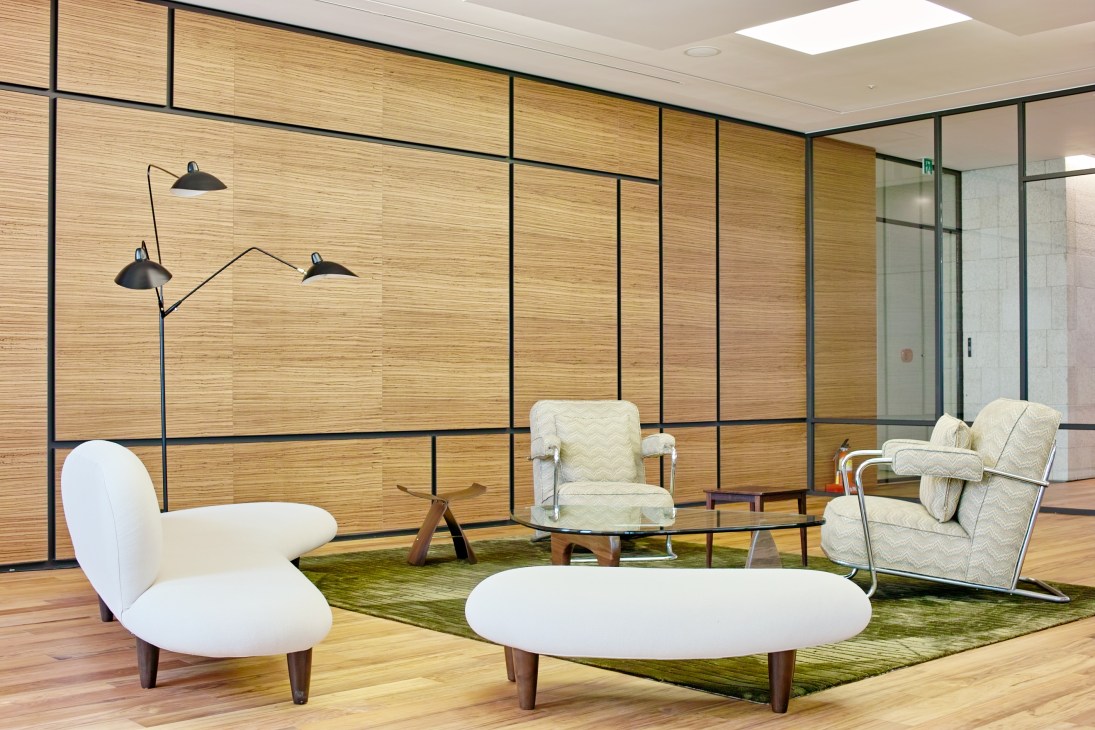 Modern guest entertaining room with mid-century furniture, wooden wall panels, and contemporary lighting fixtures.