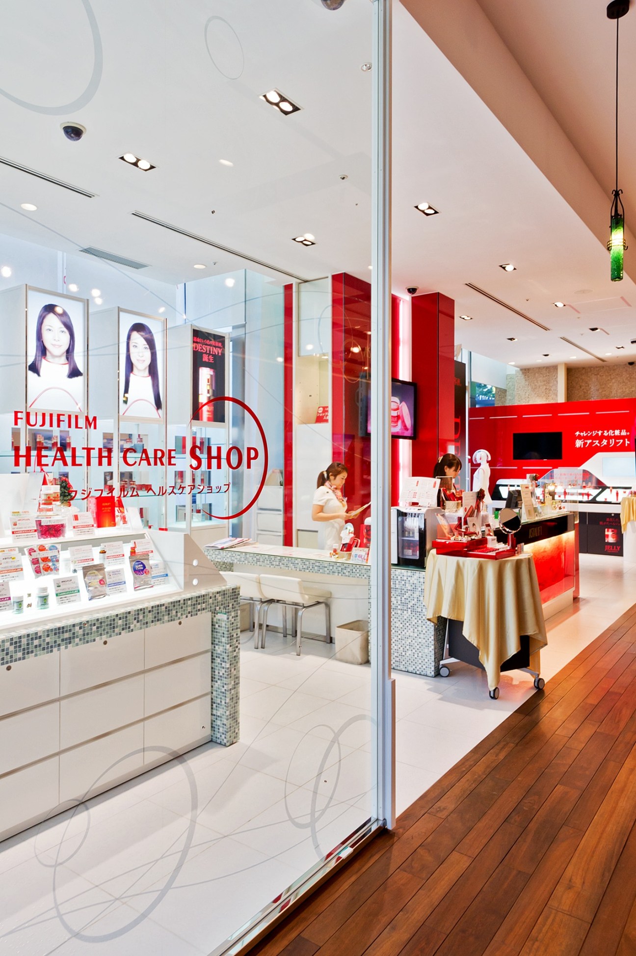 Fujifilm Health Care Shop storefront with red branding, display counters, and staff assisting customers in a modern retail space.