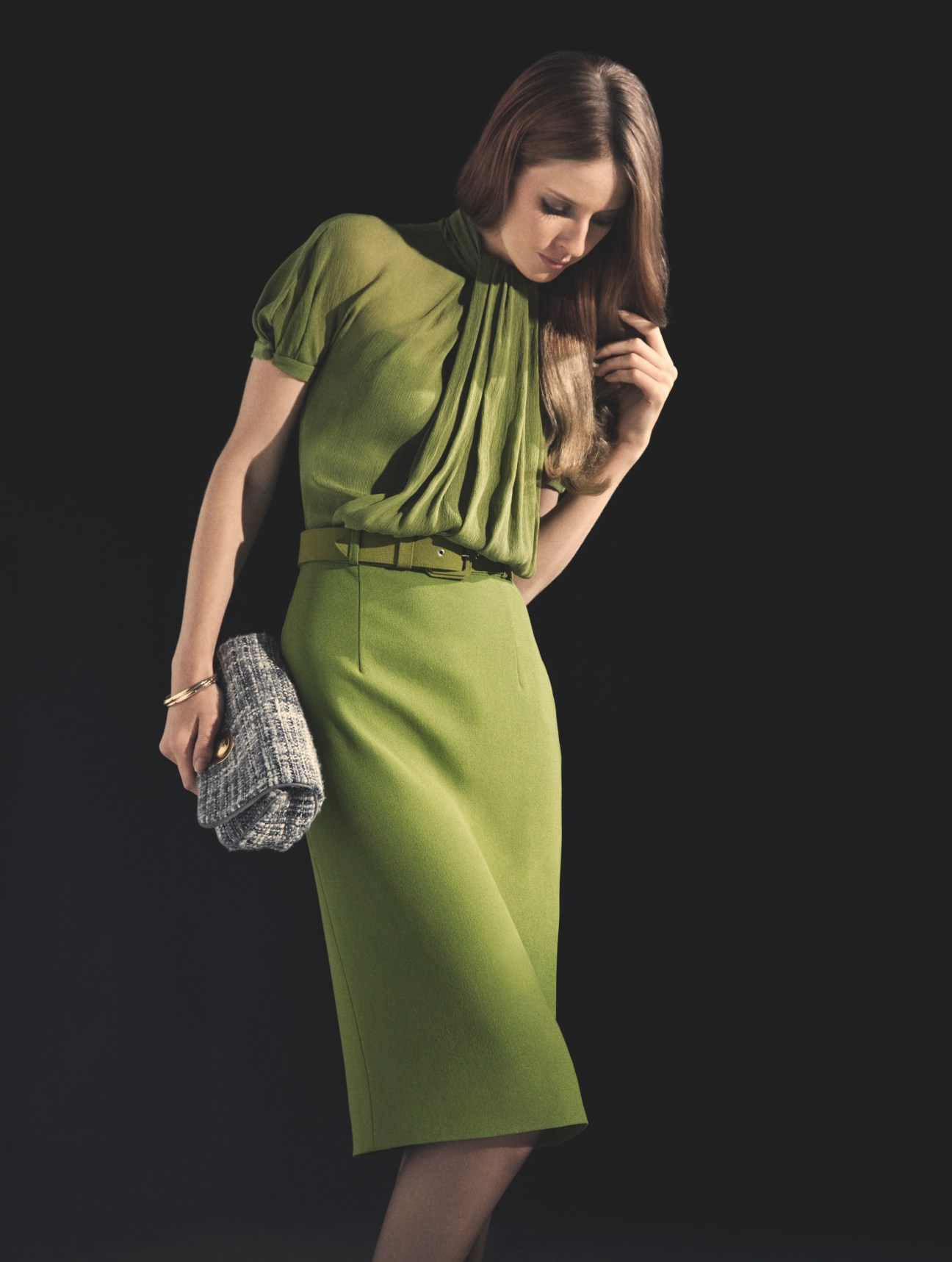Model wearing a lime green Yves Saint Laurent dress with a leather belt and grey tweed clutch bag.