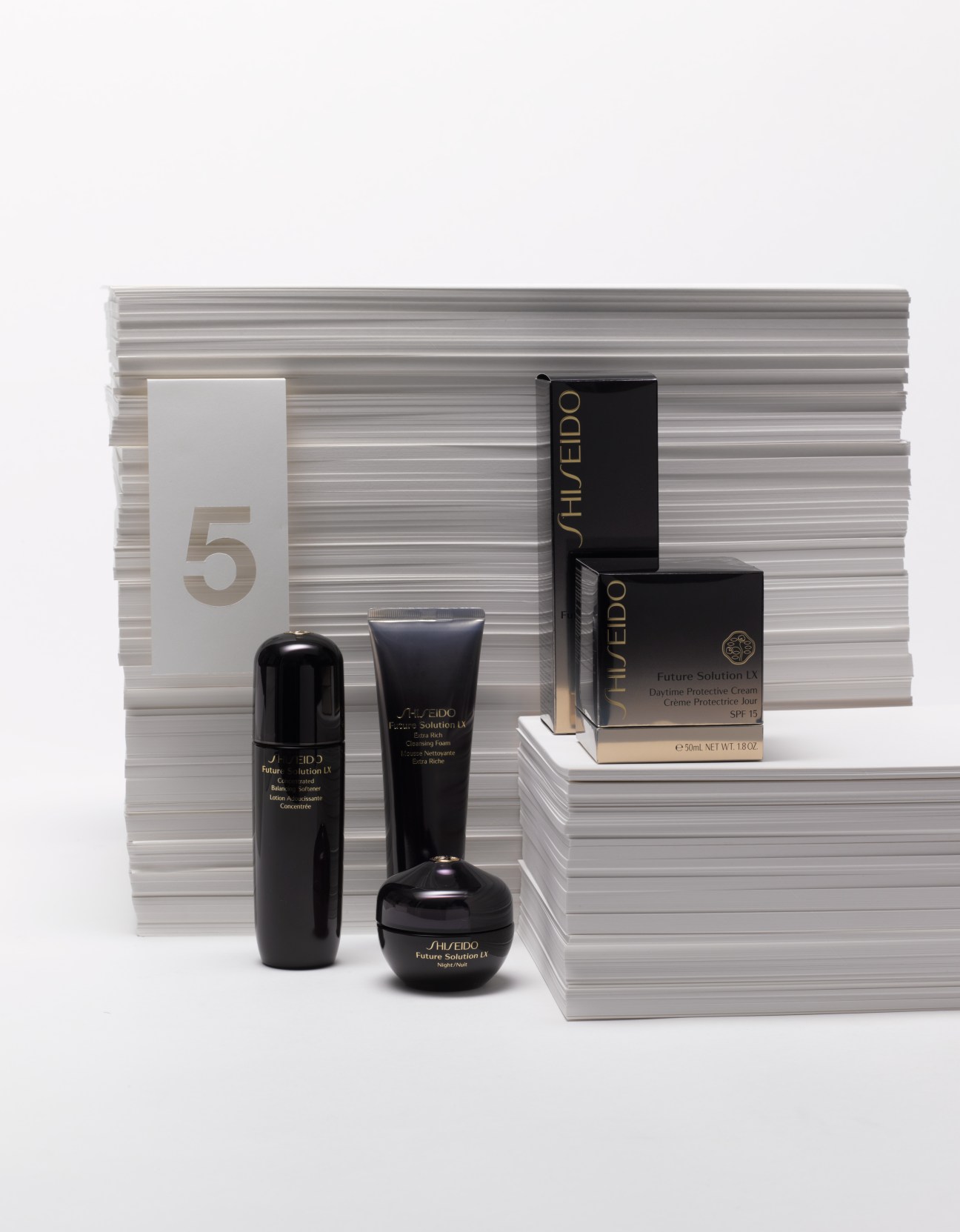 Shiseido Future Solution LX cosmetics set with black bottles and boxes displayed against striped packaging.