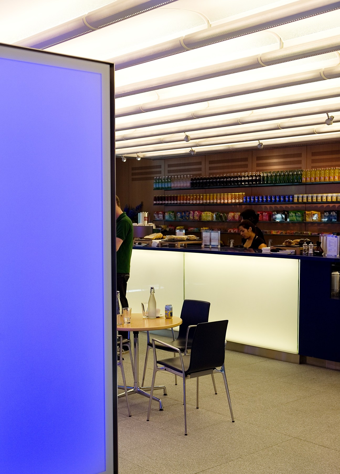 Modern café interior at Arup's London headquarters with illuminated ceiling panels, seating area, and counter service.