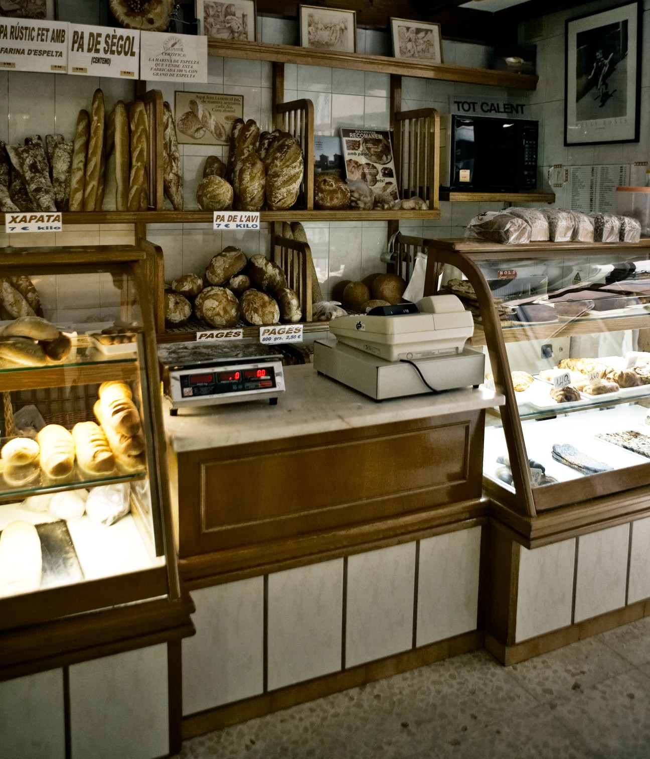 Traditional bakery display with fresh baguettes and bread in wooden shelves and glass cases.