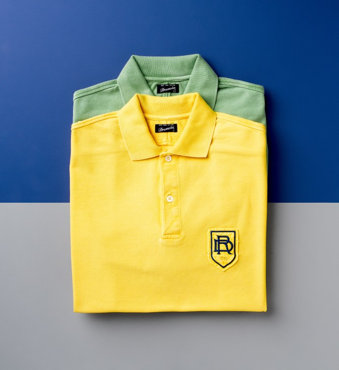 Drumohr polo shirts in green and yellow displayed flat on blue and gray background.