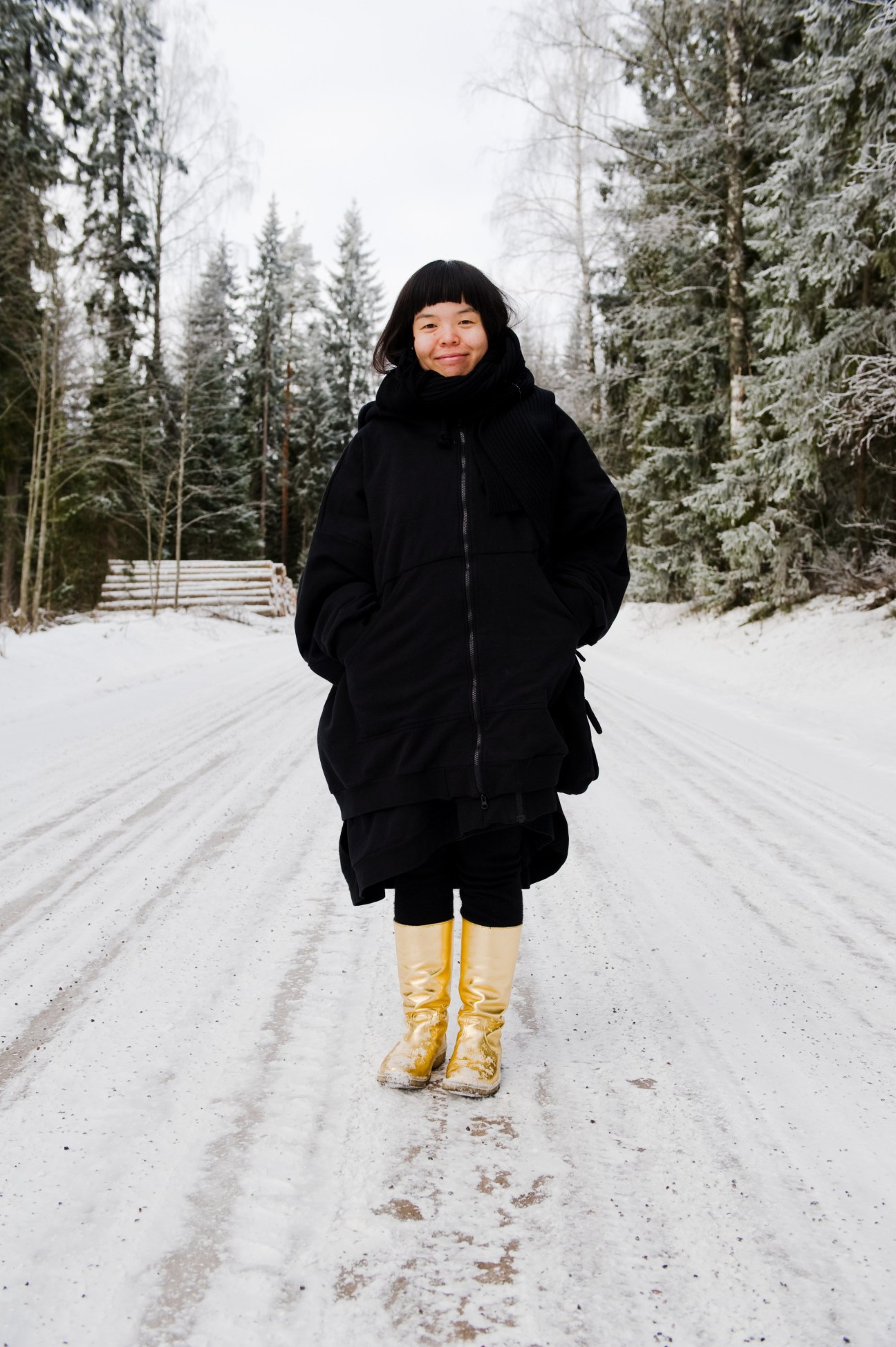 Japanese designer Nene Tsuboi wearing yellow Talla clogs on a snowy forest road in Finland.
