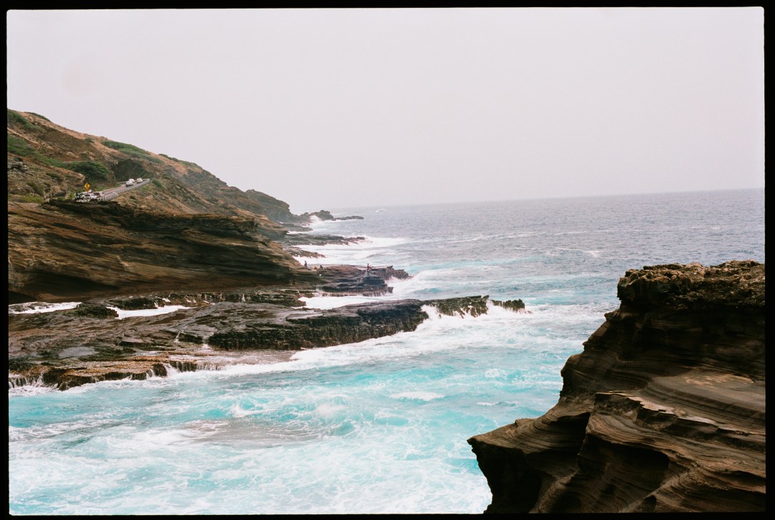 Rocky Hawaiian coastline with turquoise waves and layered stone cliffs on Lana'i island.