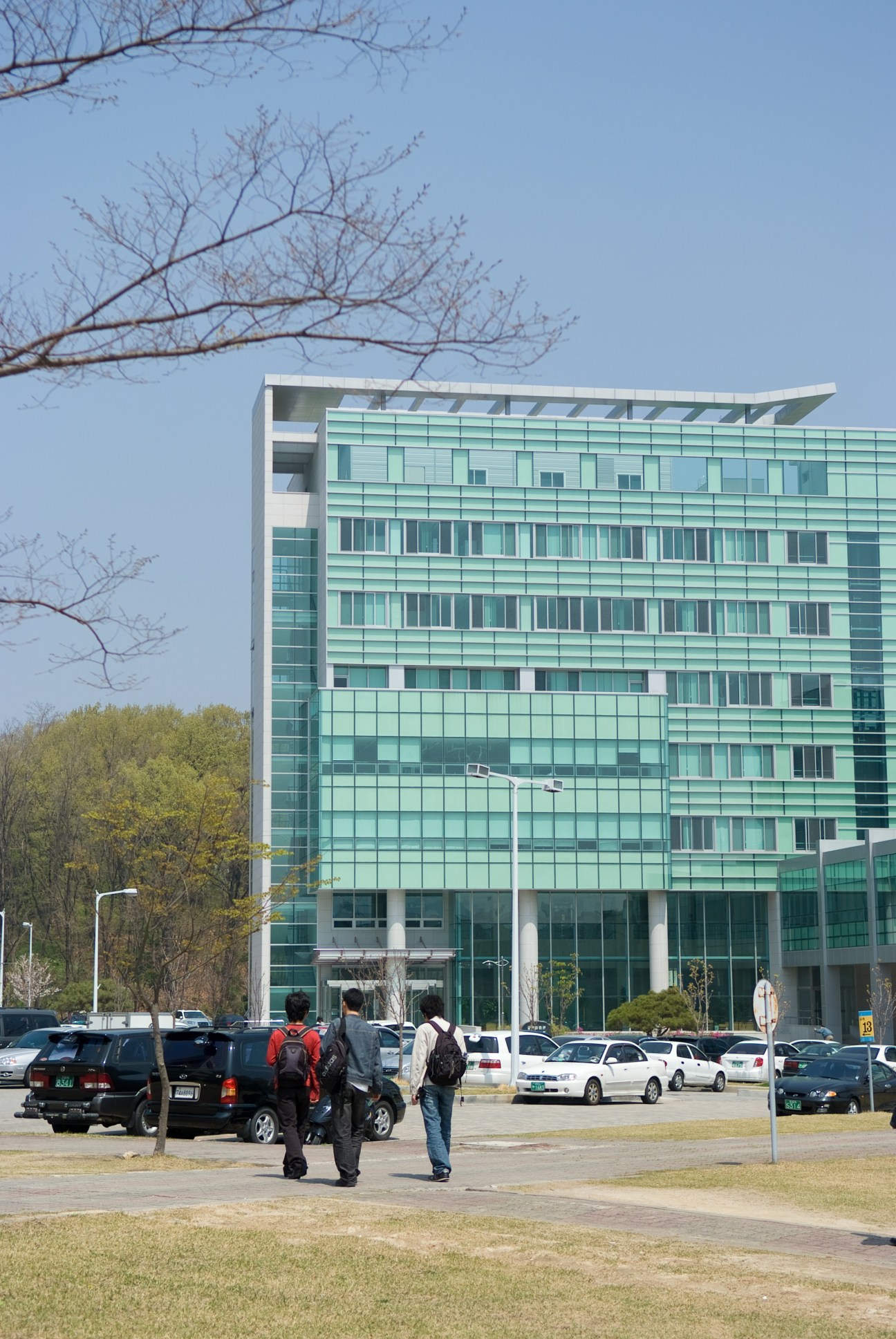 Modern glass and white building on KAIST campus with students walking in foreground.