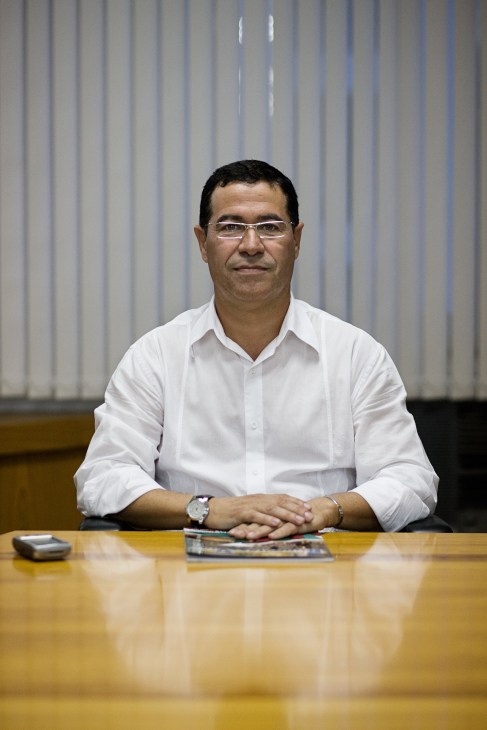 Romualdo França, president of the Santa Catarina Department of Infrastructure, sits at a wooden desk wearing glasses and a white shirt.