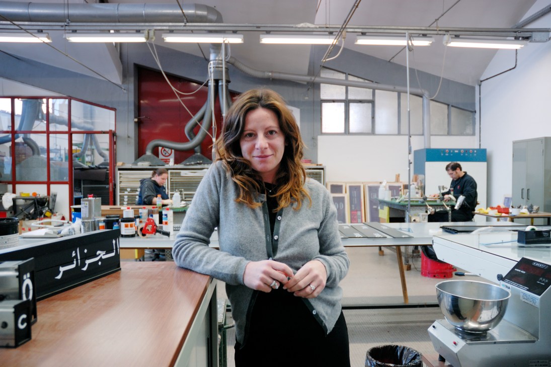 Katia Bredeon, Solari's marketing manager, stands in a factory workshop among workbenches and production equipment.