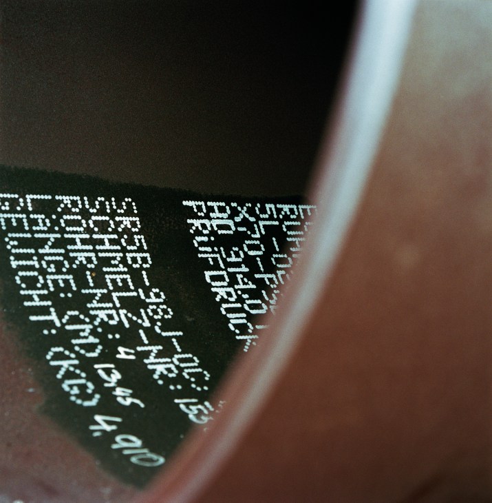 Close-up of a small cylindrical cargo tube with illuminated text markings on its surface.