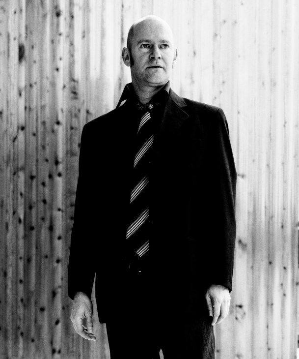 Black and white portrait of Andrew Page, a primary teacher and artist, wearing a dark blazer with striped tie.