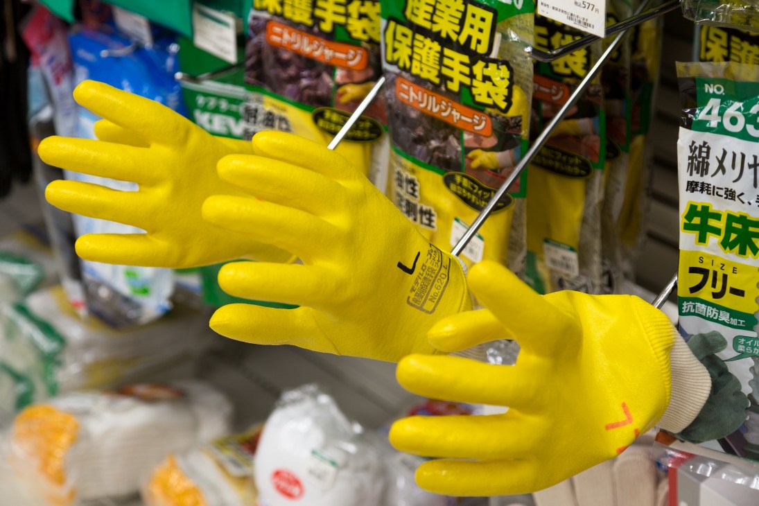 Yellow rubber gloves displayed among household cleaning products with Japanese labels.