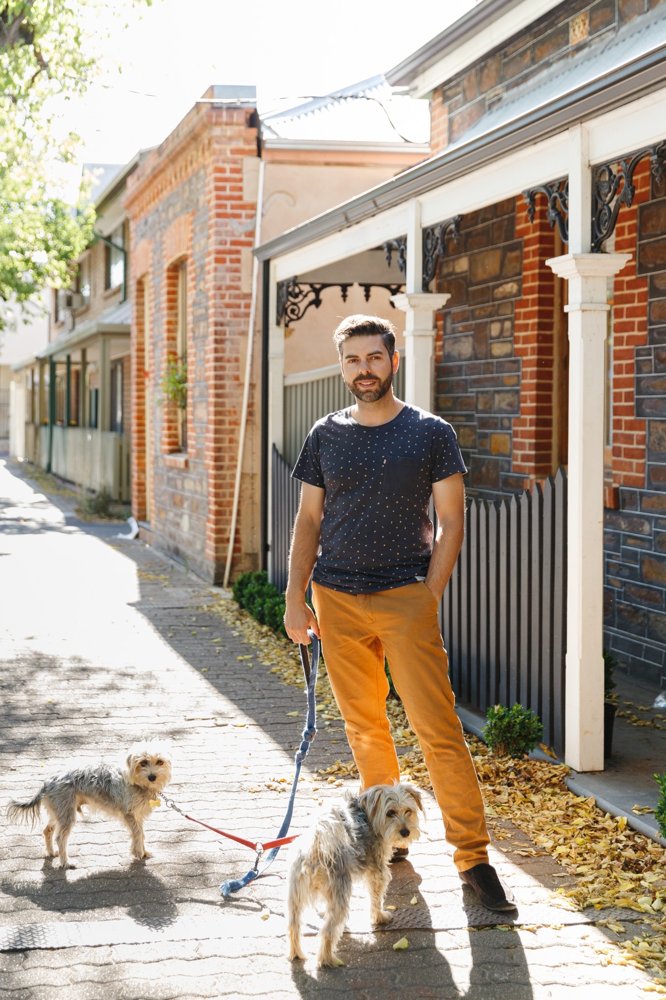 Southwest resident Jeevan Deut stands with two dogs on a brick-lined alley lined with Victorian cottages in Adelaide's southwest corner.