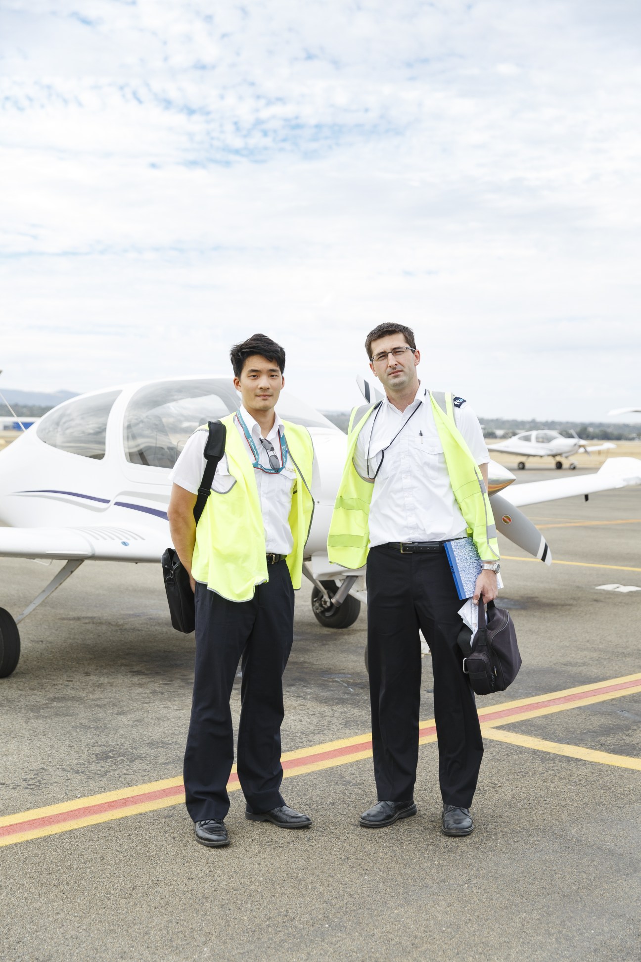 Alex Leung and instructor Zoran Miletic stand on the tarmac wearing high-visibility vests in front of a Diamond DA40 aircraft.