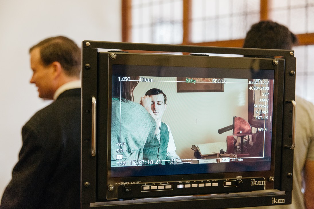 Film crew monitoring video playback on an Ikan monitor display during production.