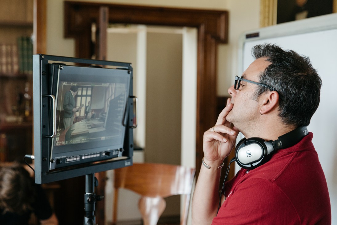 Film editor wearing headphones monitors footage on a display screen during post-production work.