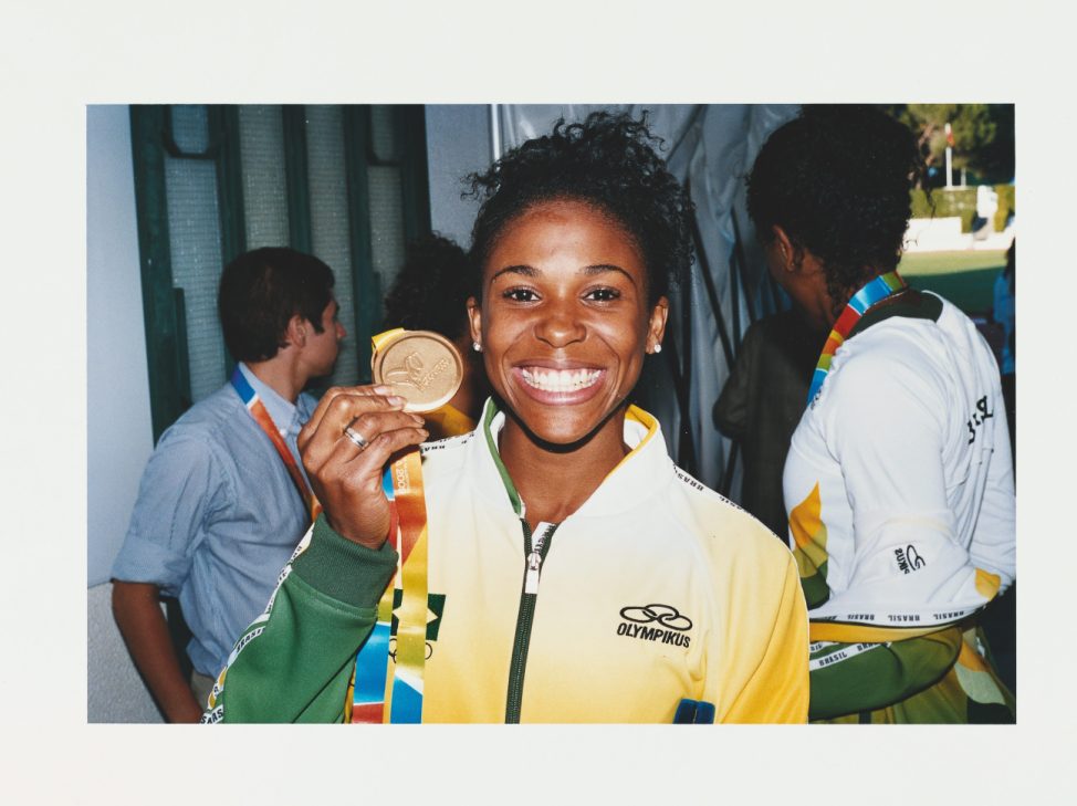 Brazilian athlete holding a gold medal while wearing a yellow and green tracksuit.