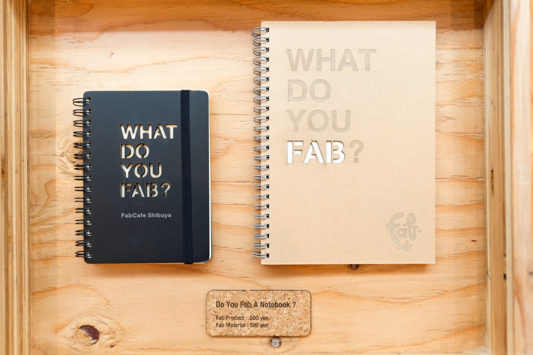 Two spiral-bound notebooks with "What do you fab?" text displayed on wooden surface.