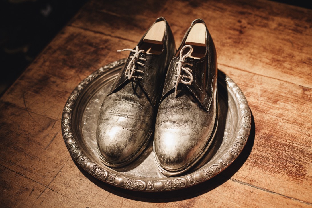 Hand-crafted black leather oxford shoes displayed on an ornate silver tray