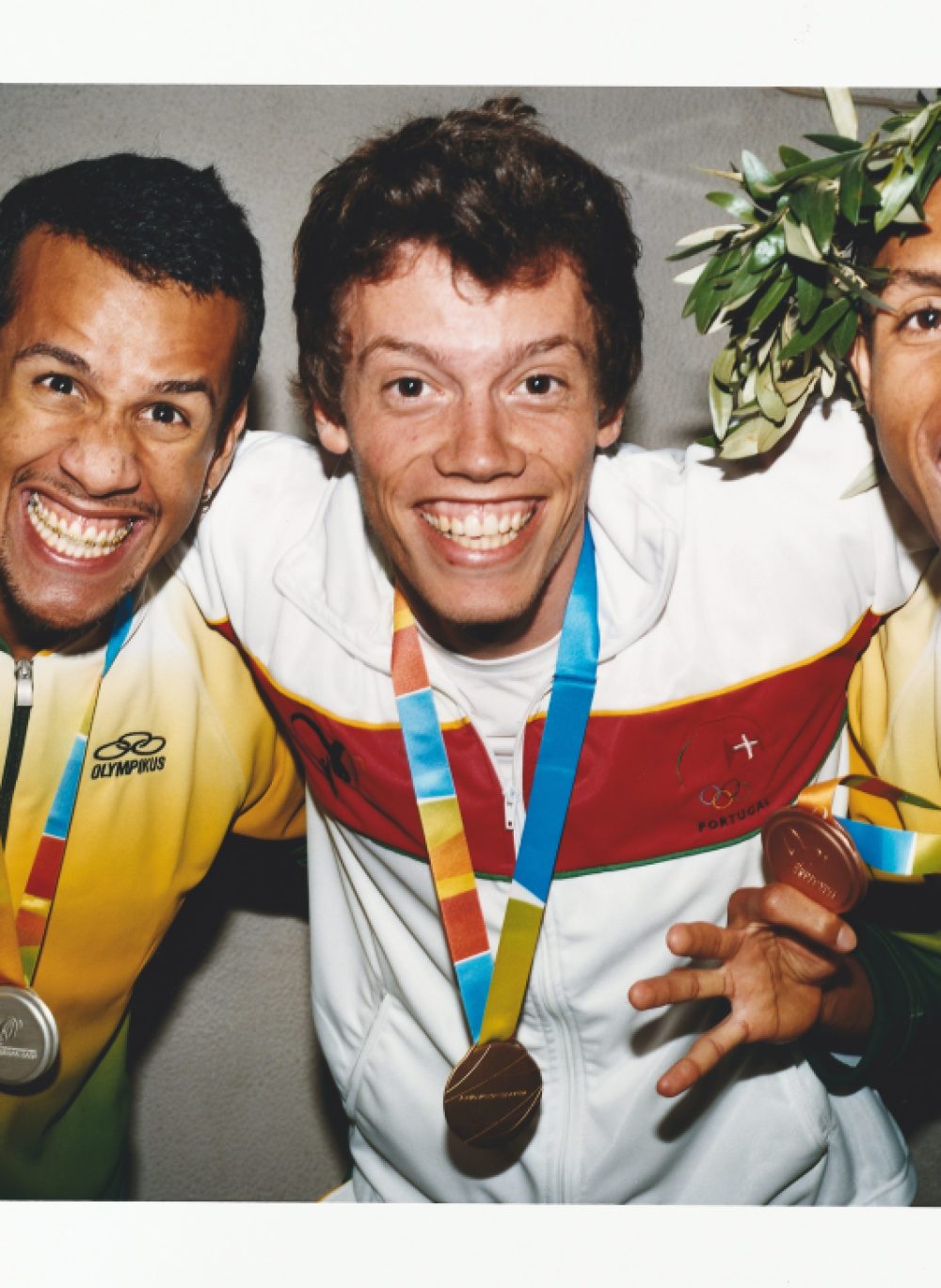 Three smiling athletes with medals standing on a podium after winning the 100m race at the Jogos da Lusofonia.
