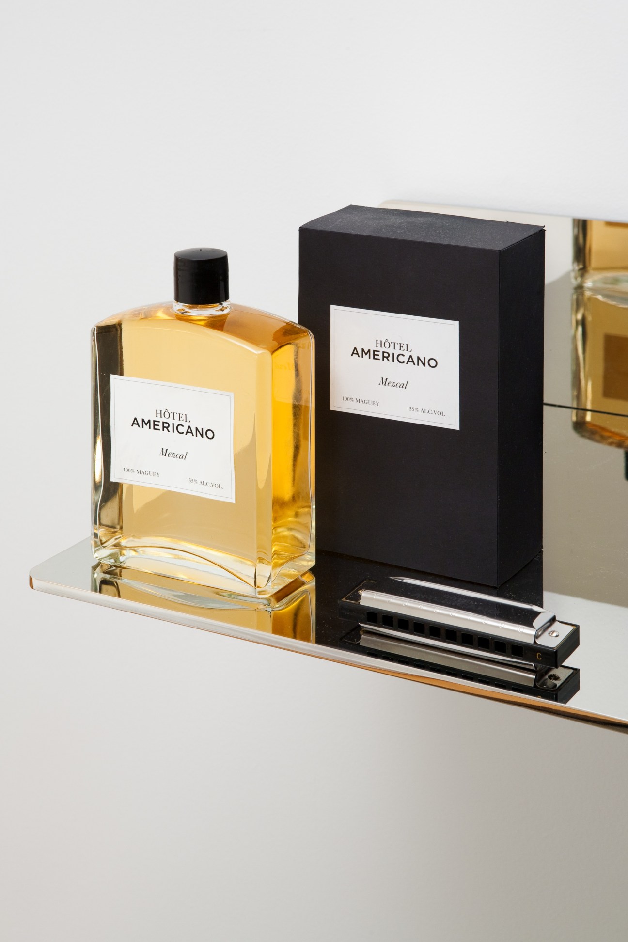 Hôtel Americano own brand mezcal bottle and black box packaging displayed on a marble surface.