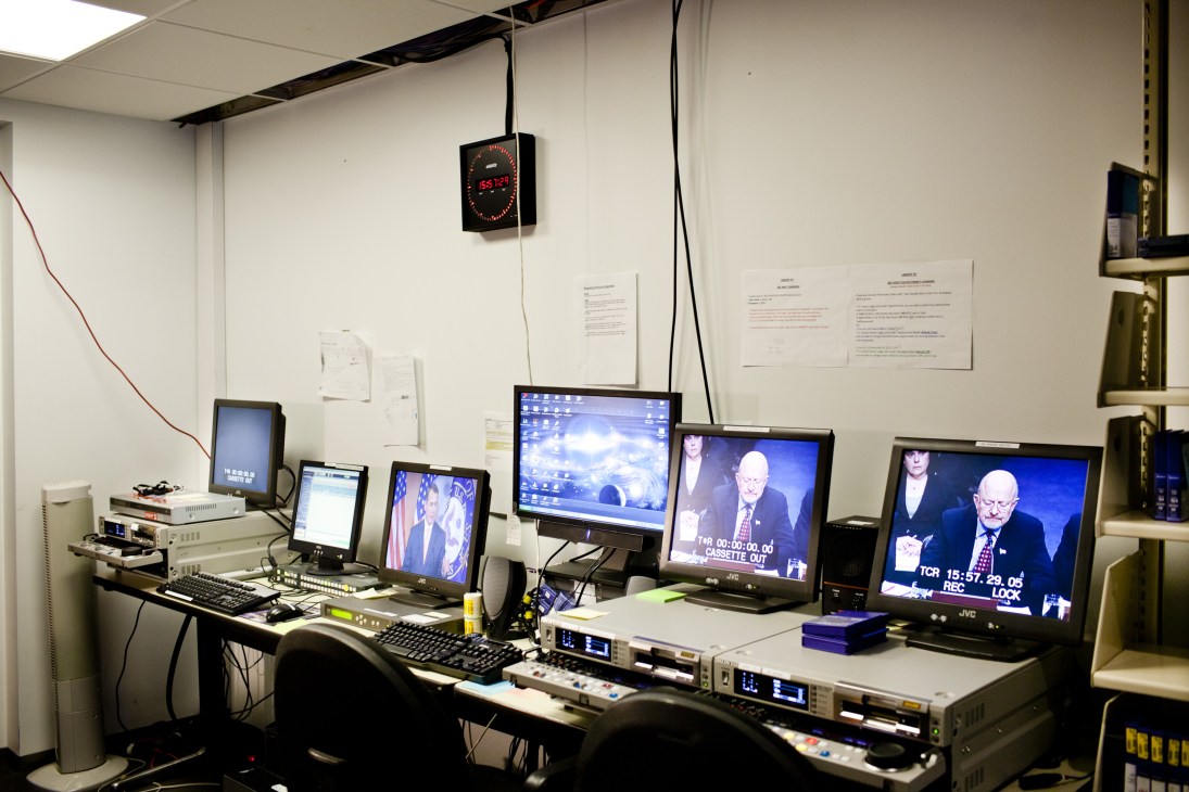 Control room with multiple monitors displaying news broadcasts and editing equipment on desk