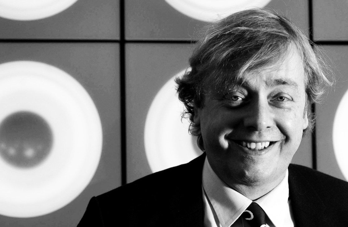 Black and white portrait of Alistair Hicks, art adviser to Deutsche Bank, smiling at the camera.