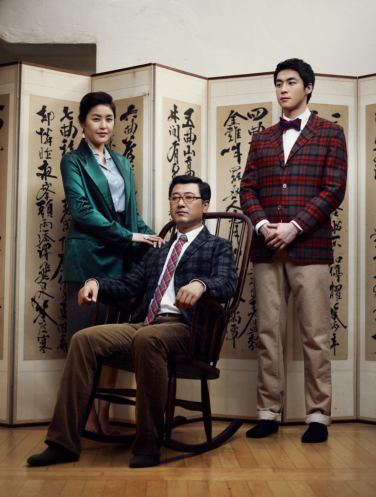 Family of three posing in front of traditional Korean calligraphy panels for a fashion editorial.