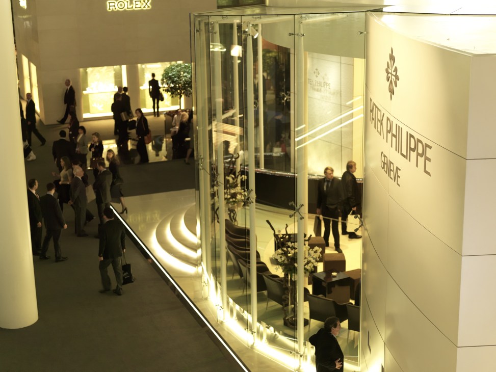 Patek Philippe stand at BaselWorld with visitors and illuminated display cases.