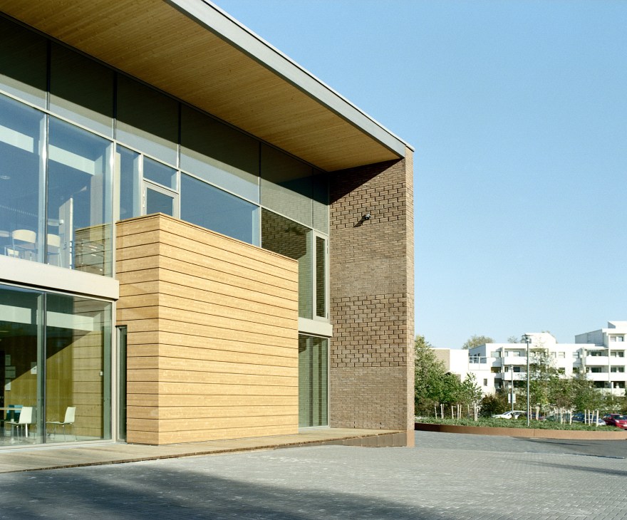 Modern school building exterior with brick, oak cladding and glass windows under clear sky.