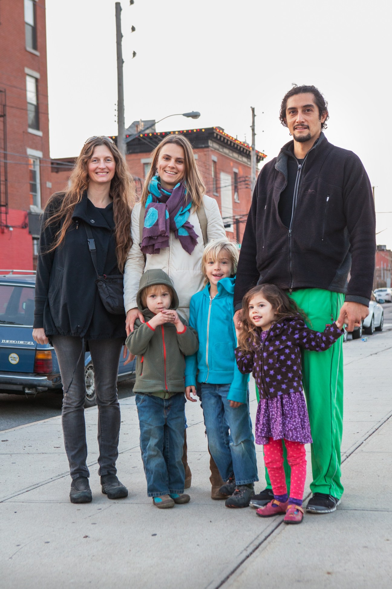 A family of two adults and four children standing on a Red Hook street with brick buildings behind them.