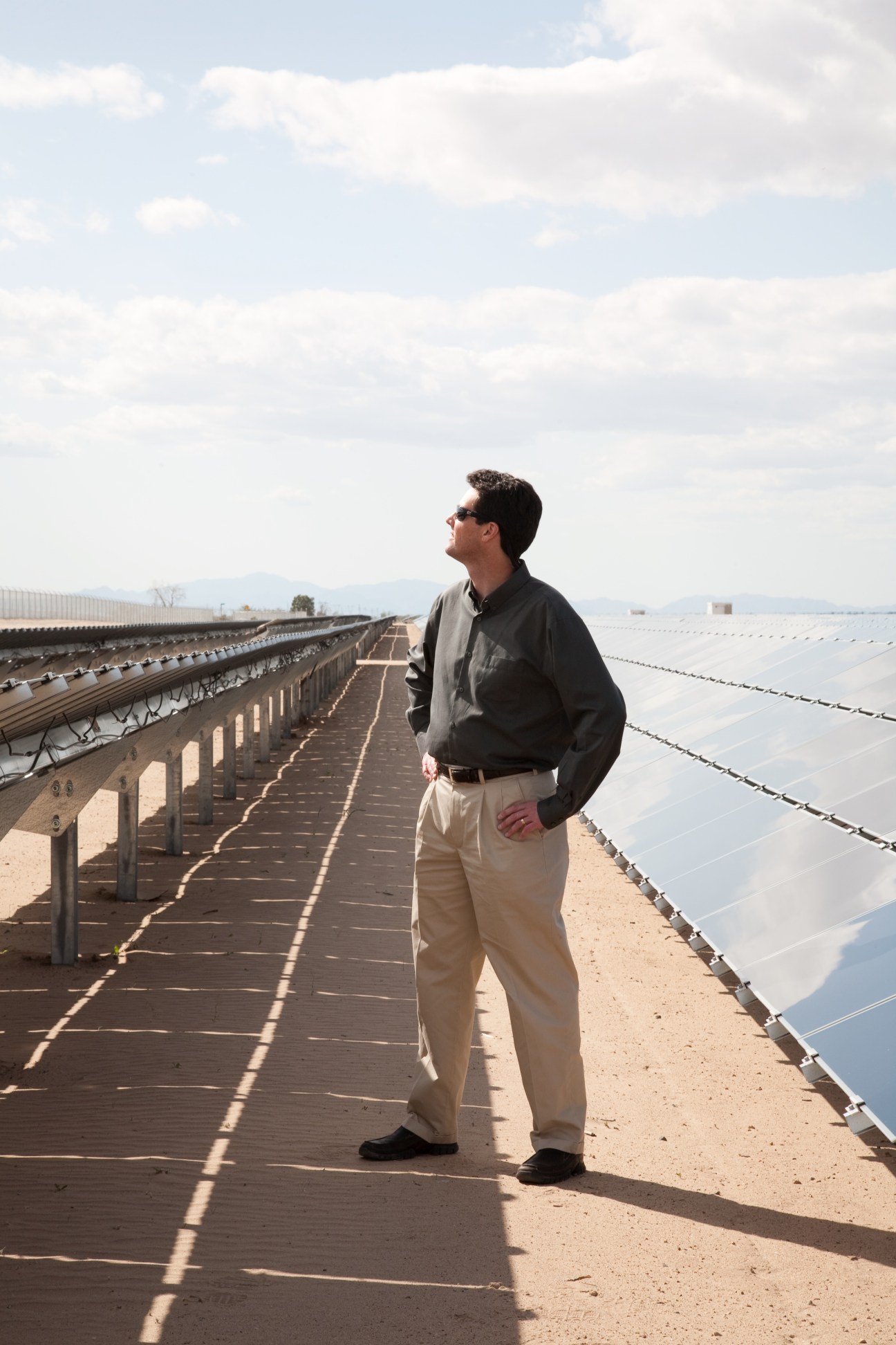 Tim Hemig, vice president of NRG Solar, stands on a walkway between rows of solar panels in the desert.