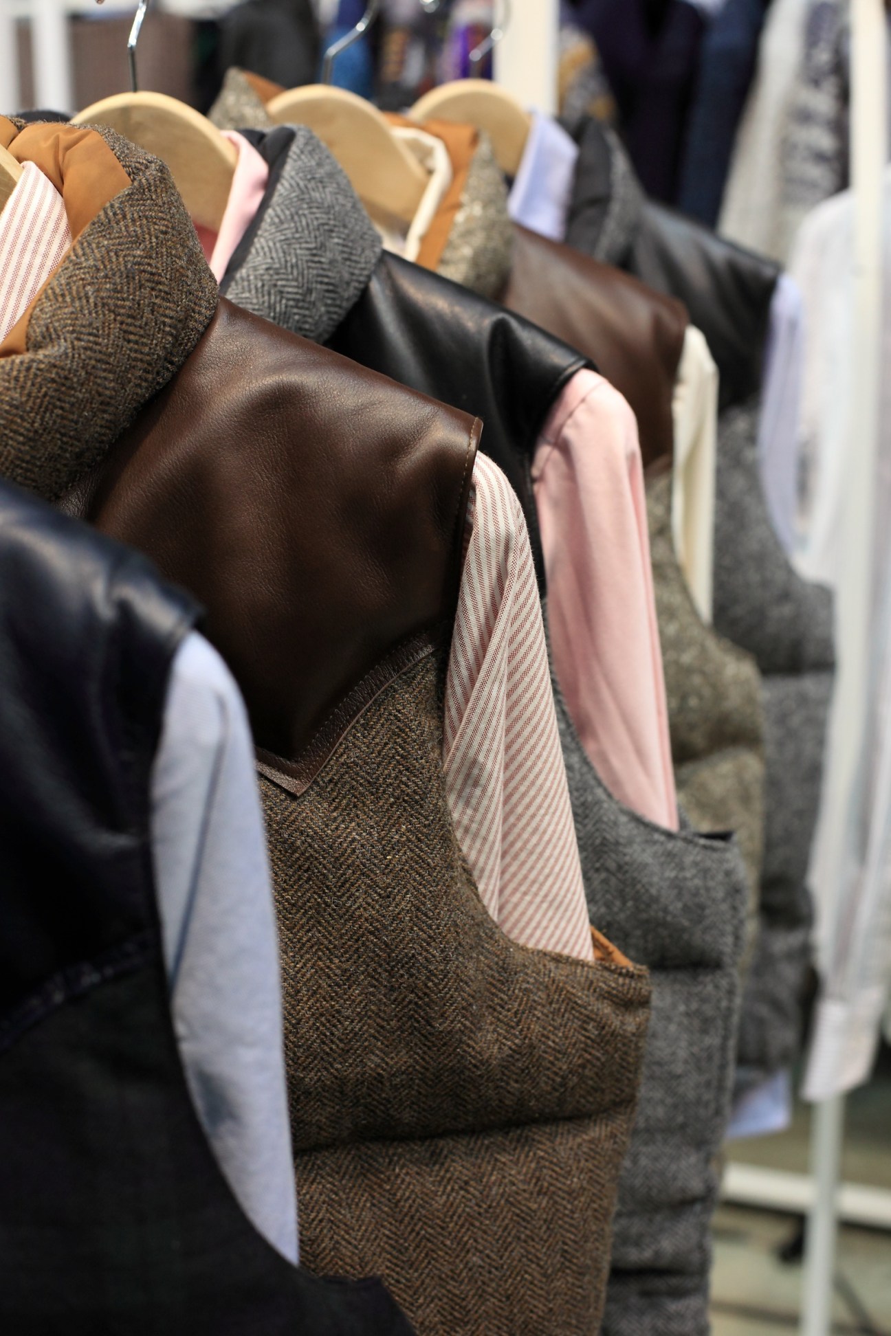 Rocky Mountain gilets displayed on wooden hangers at a trade fair, showing layered outerwear with leather yoke details.