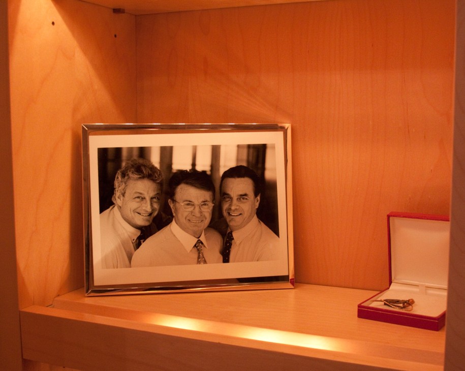 Framed photograph of three men displayed on an illuminated orange shelf at Clarins headquarters.