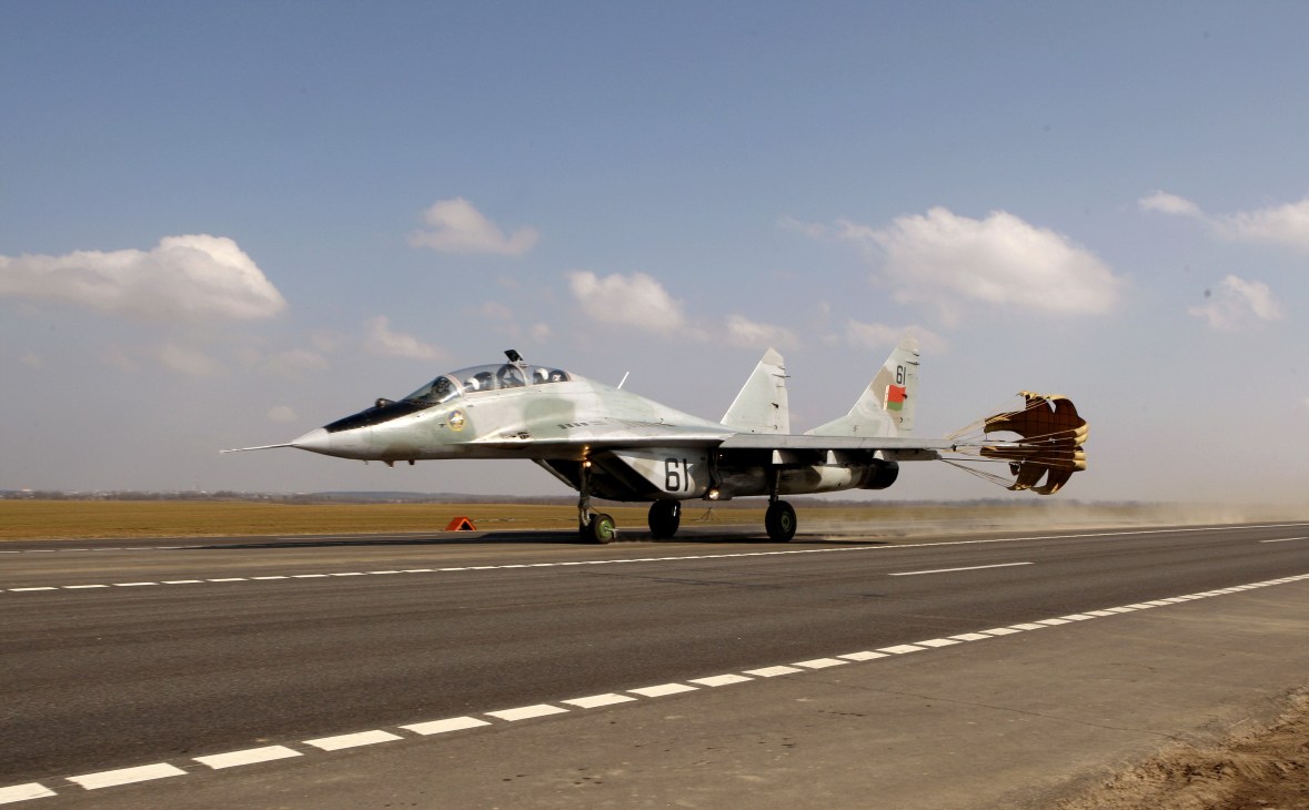 Russian MiG-29 fighter jet on runway with deployed parachute brakes.