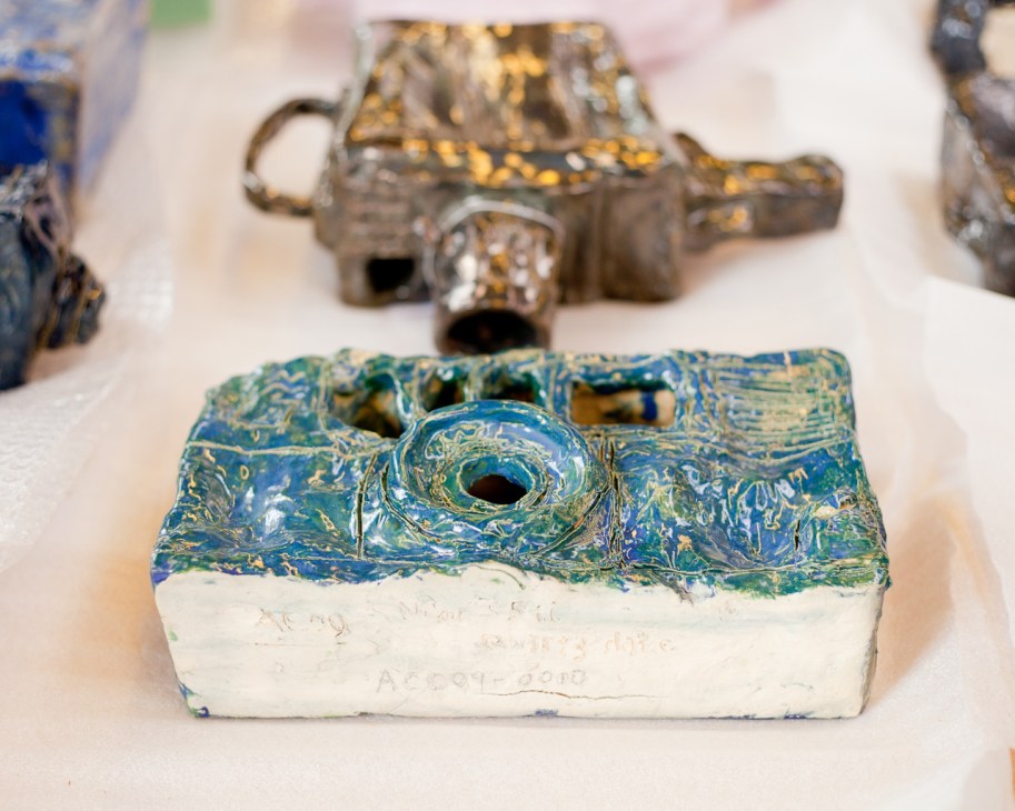 Handmade cameras by Alan Constable with blue and green painted surfaces and white bases.