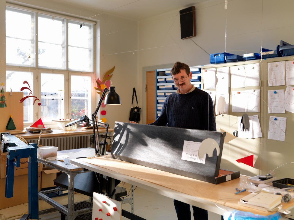 Finn Andersen holds a large mobile component in his workshop at Flensted Mobiles.