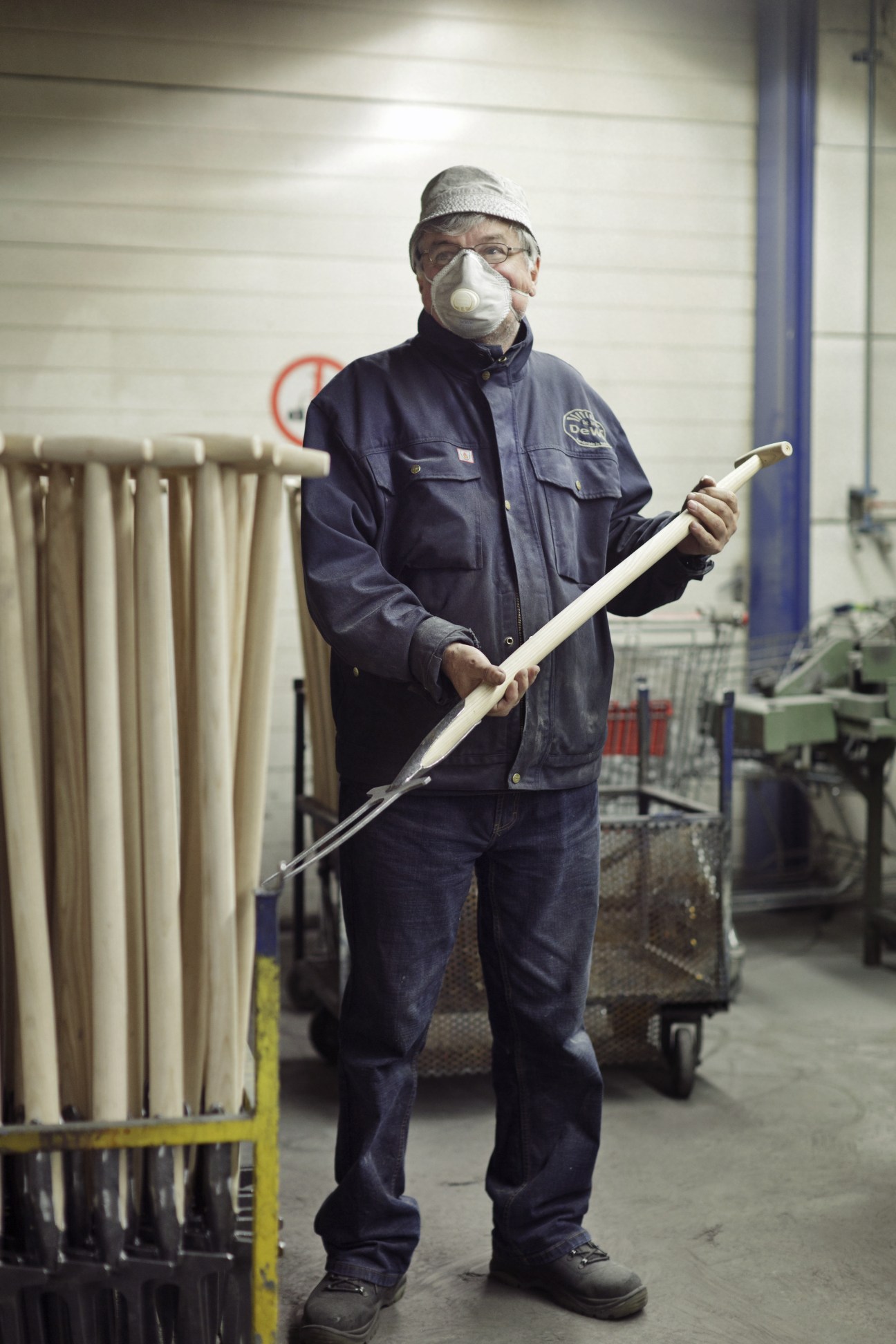 DeWit factory worker holding a finished garden tool with wooden handle in the workshop.