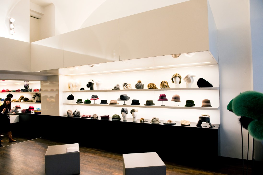 The Mühlbauer flagship store displaying handmade hats on illuminated shelves with a black counter.