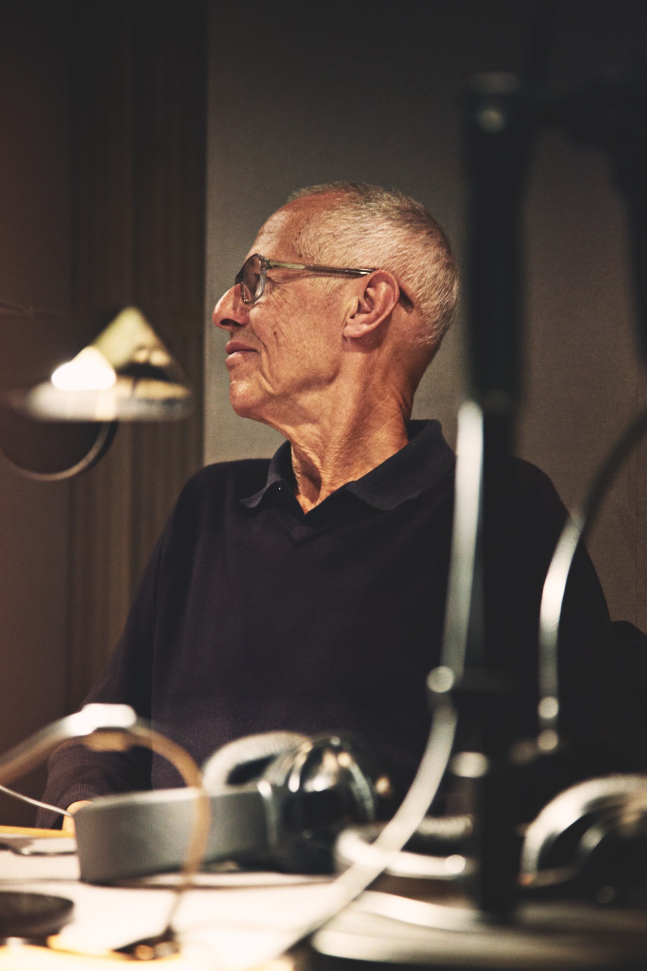 Graham Cutler of Cutler & Gross wearing glasses at a radio studio desk with headphones and microphone.