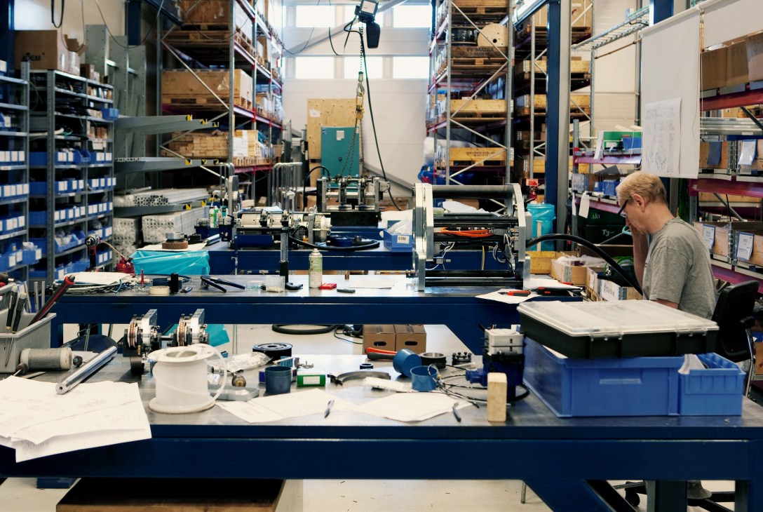 A Tolerans stitching machine being assembled on a blue workbench in a factory workshop.