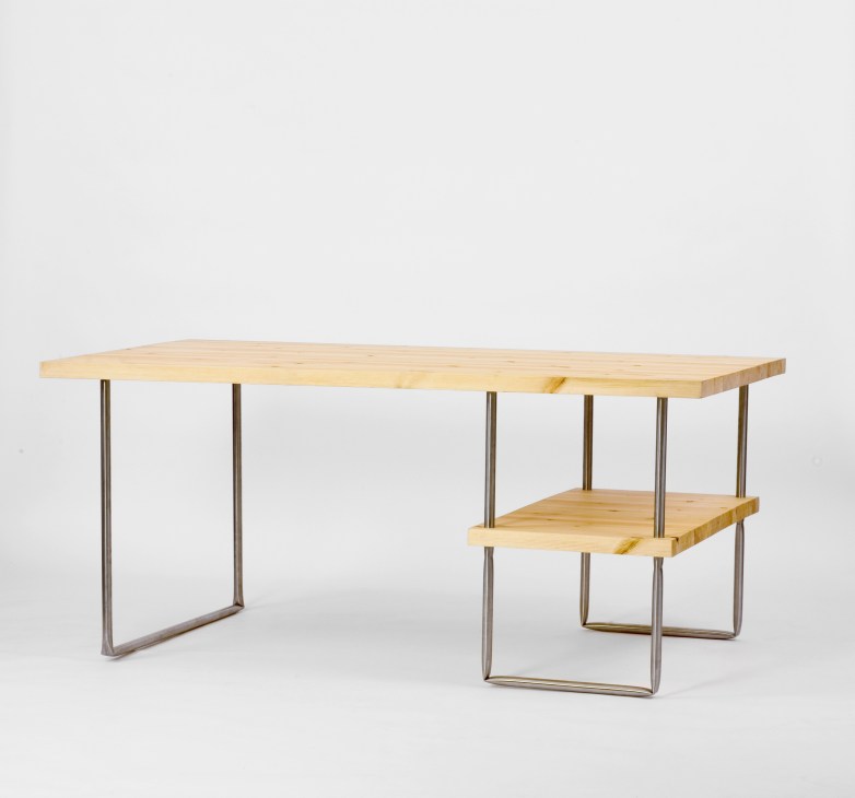 Wooden desk with folded tubular steel base and integrated lower shelf against white background.