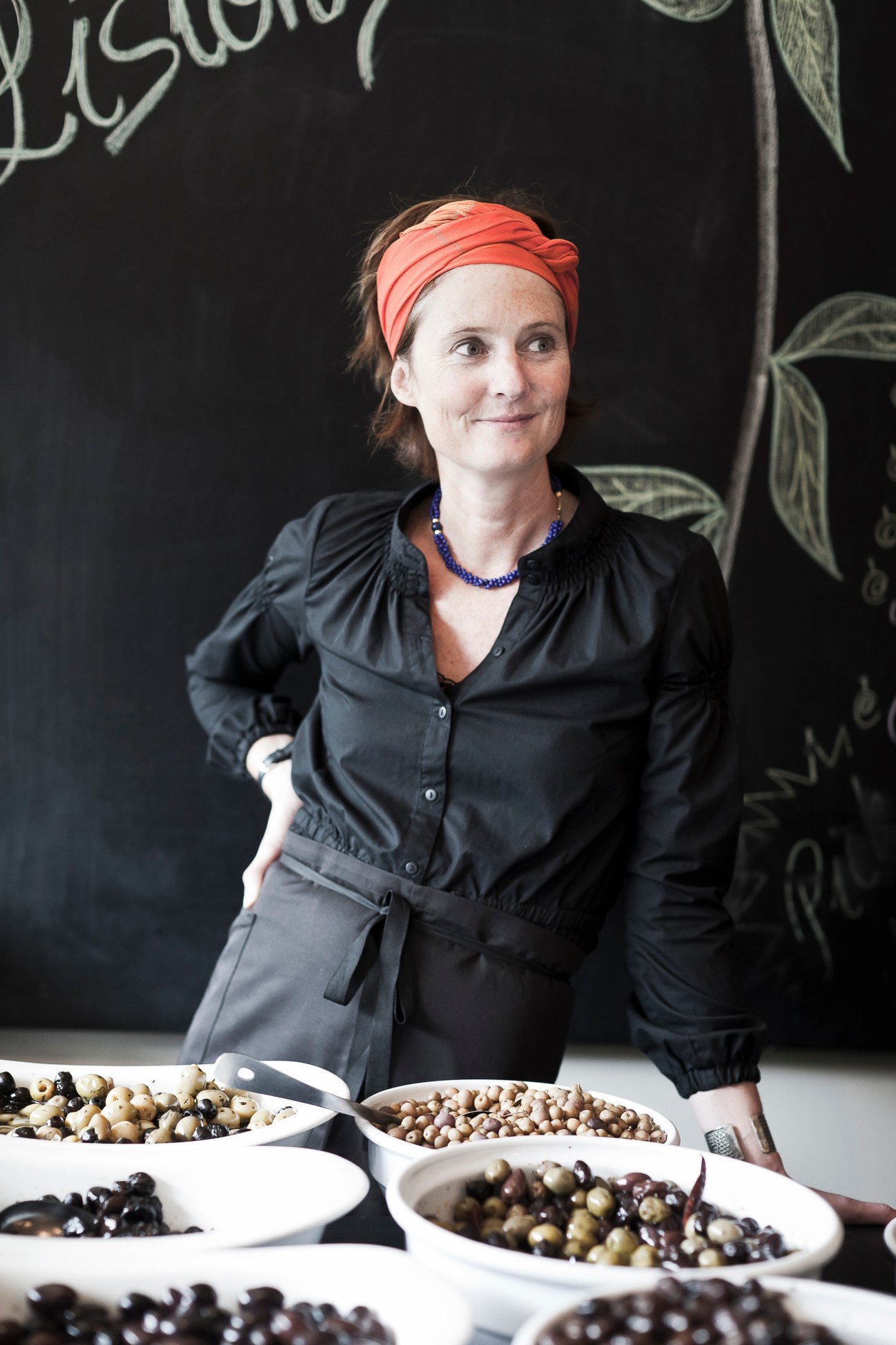 Karen Liston, owner of Listons Food, stands behind bowls of locally sourced olives and products.