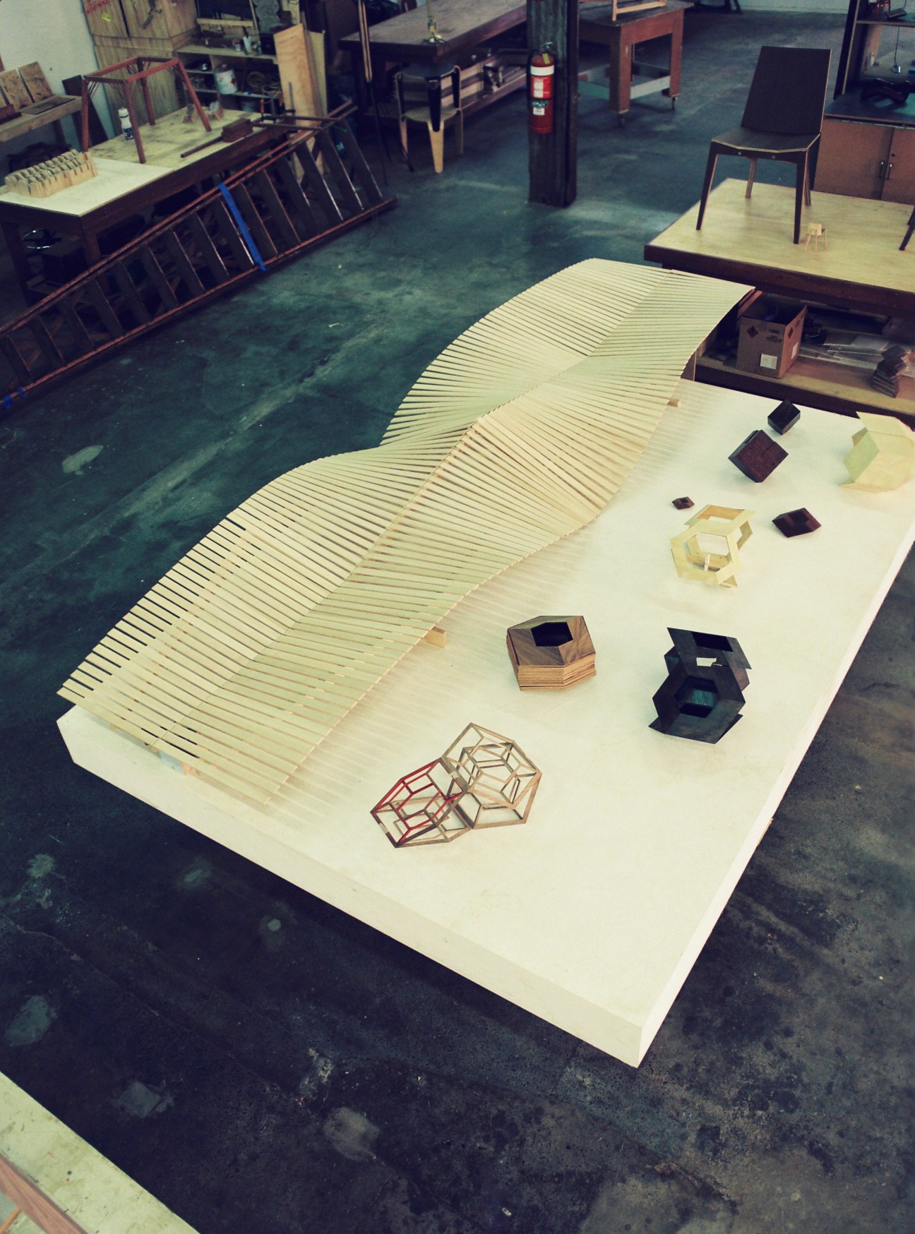 Worktable displaying Nick Statham's sculptural wooden installation in American maple alongside various geometric wood pieces.