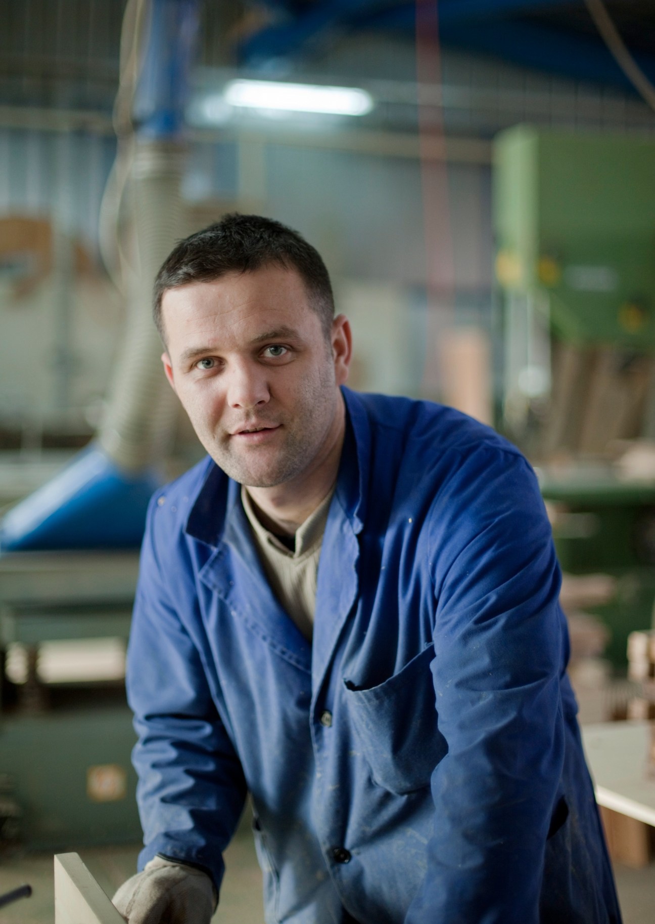 Man in blue work jacket posing in Rukotvorine woodcarving workshop.