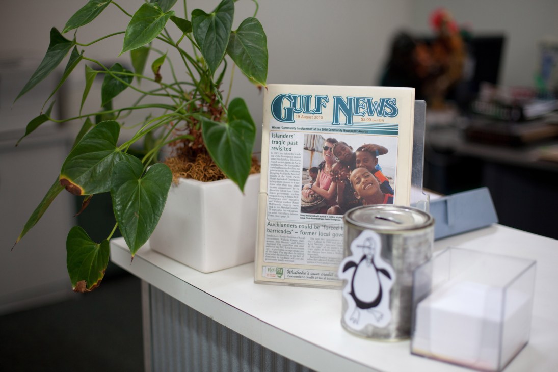Gulf News newspaper displayed on an office desk with a potted plant and cup nearby.