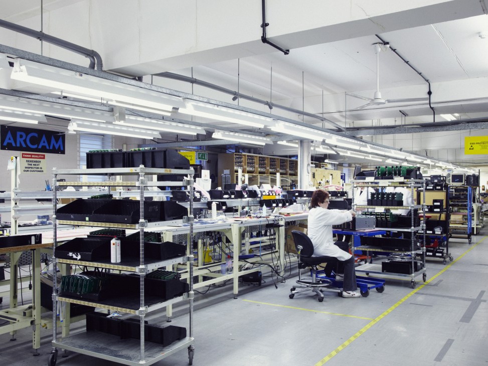Arcam factory floor with worker assembling hi-fi equipment on industrial shelving.